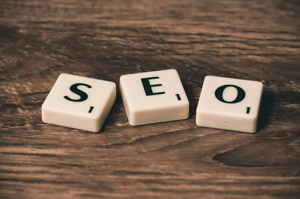 Letter tiles spelling the acronym “SEO” on a wooden surface, representing search engine optimization.